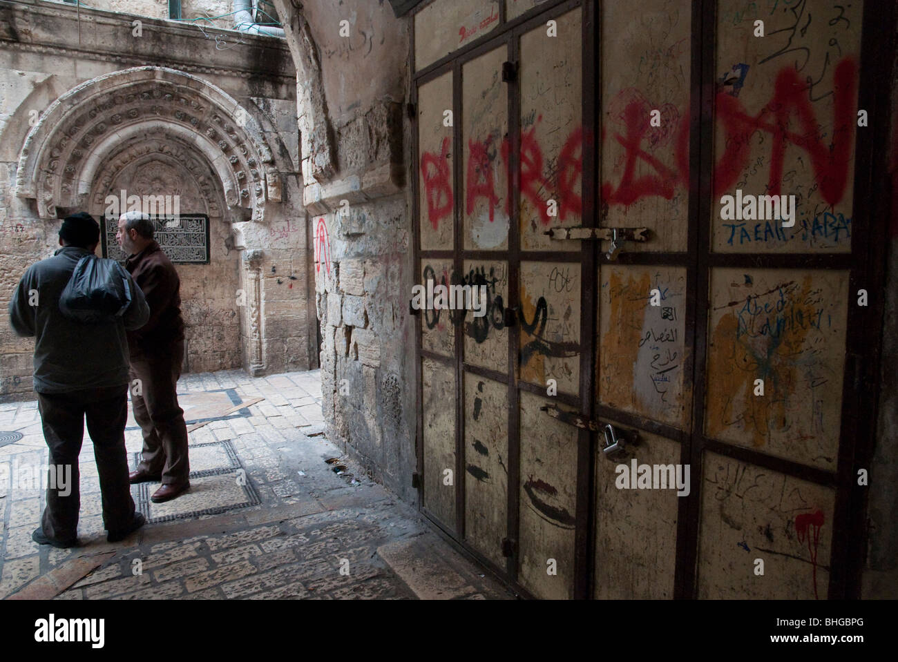 Due uomini palestinesi parlano accanto a persiane chiuse in Gerusalemme la città vecchia Foto Stock