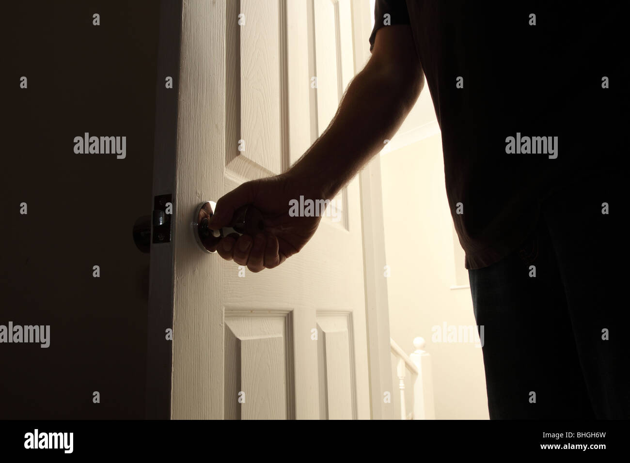 Mano d'uomo di apertura di una porta di una stanza buia la notte Foto Stock