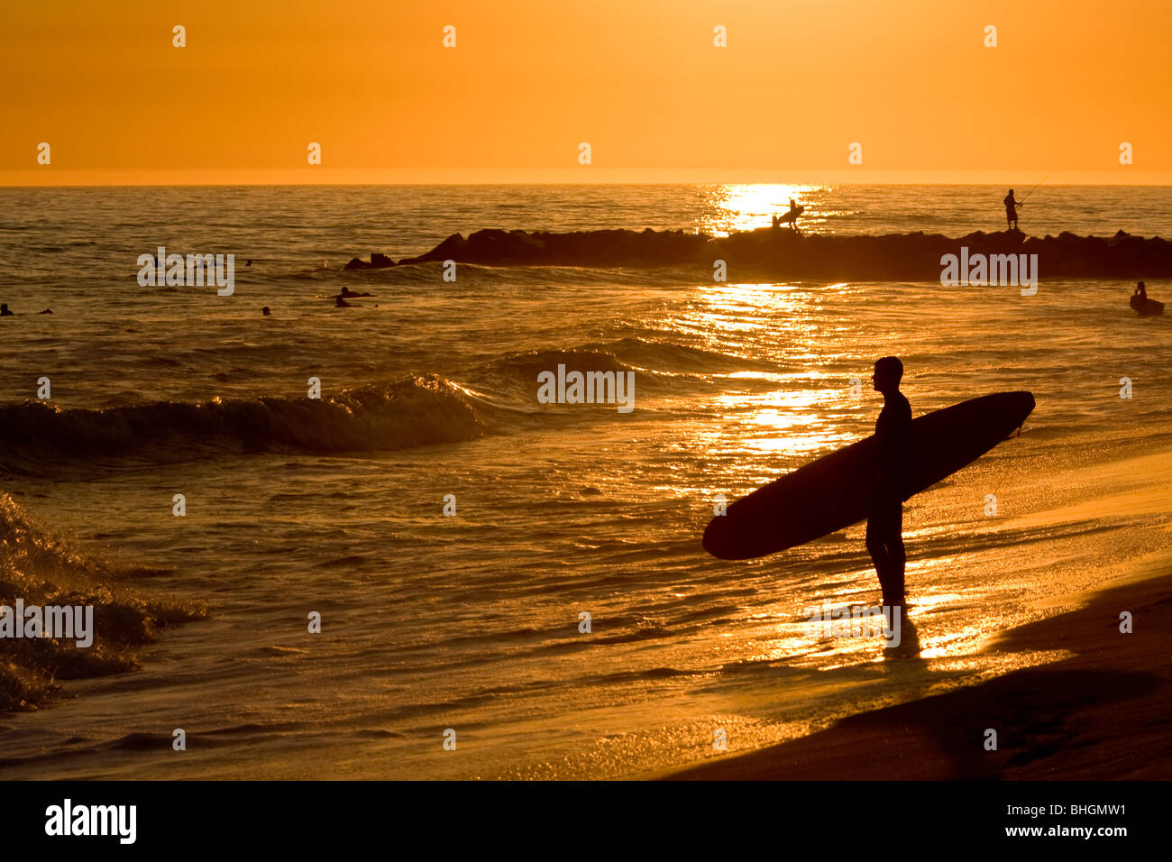 Surfer al tramonto sulla spiaggia. Foto Stock