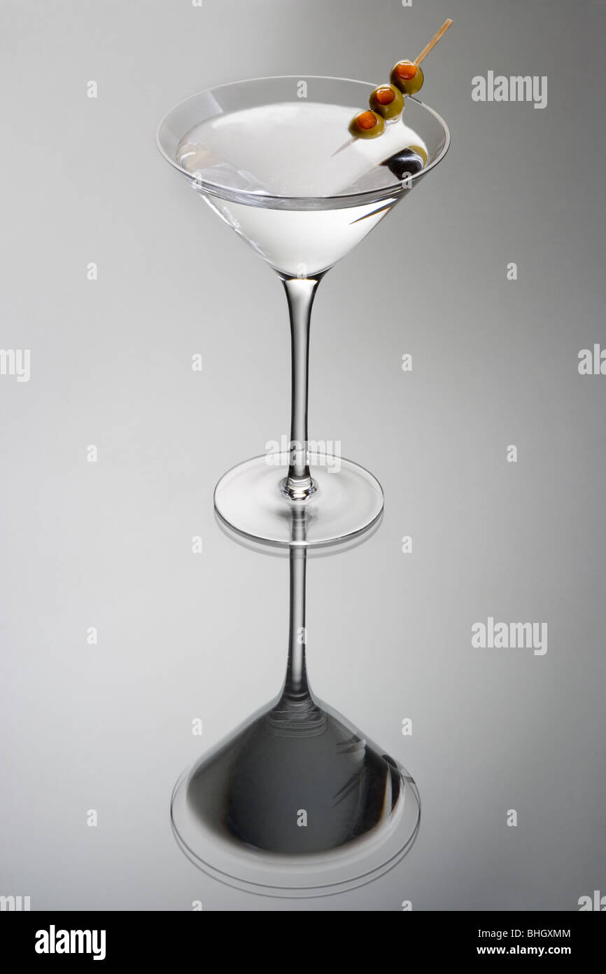 Martini bevanda miscelata con olio di oliva guarnite su uno sfondo grigio chiaro con la riflessione Foto Stock