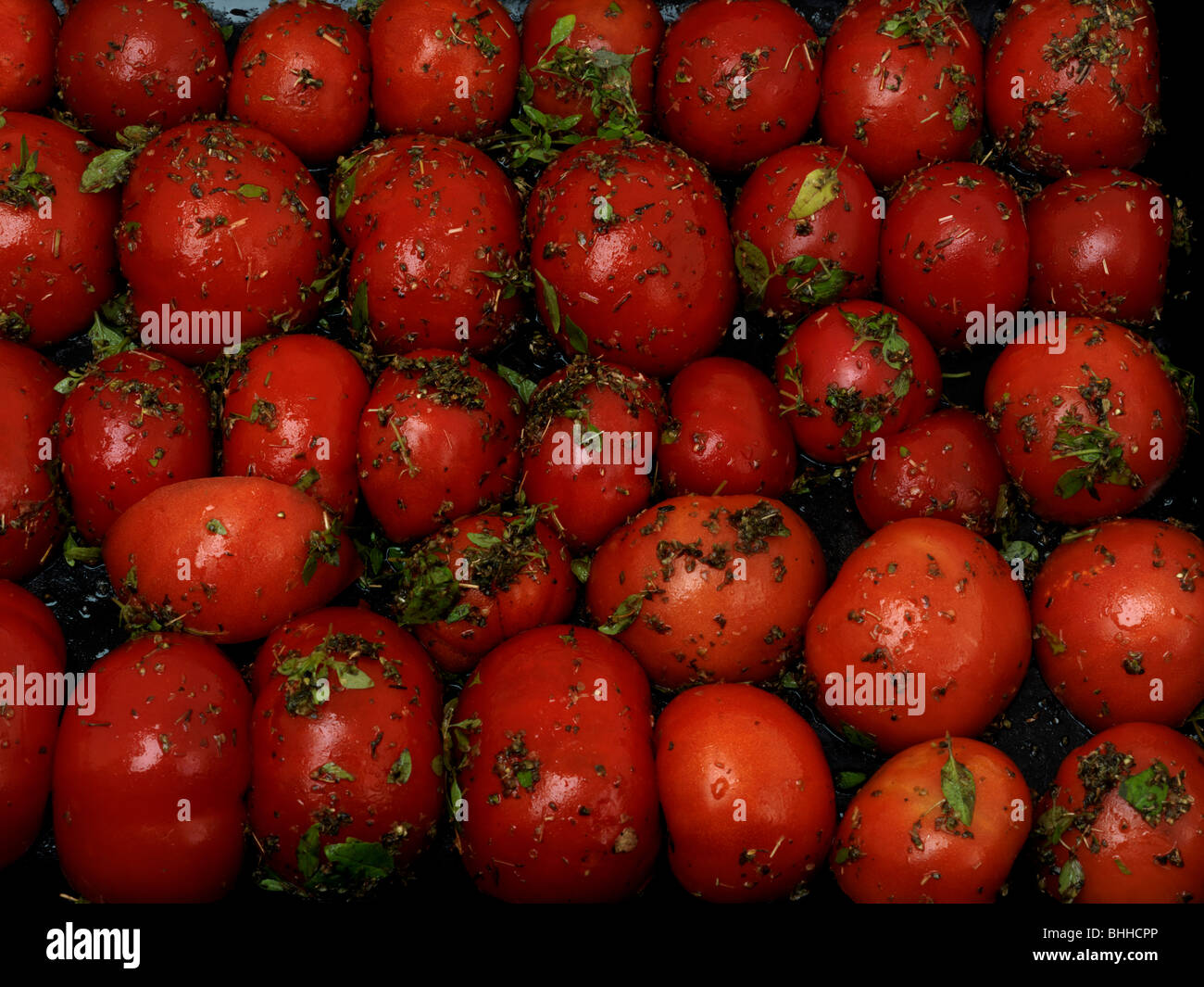Un vassoio di pomodori cresciuti in casa con basilico e olio di oliva preparato per essiccamento in forno Foto Stock