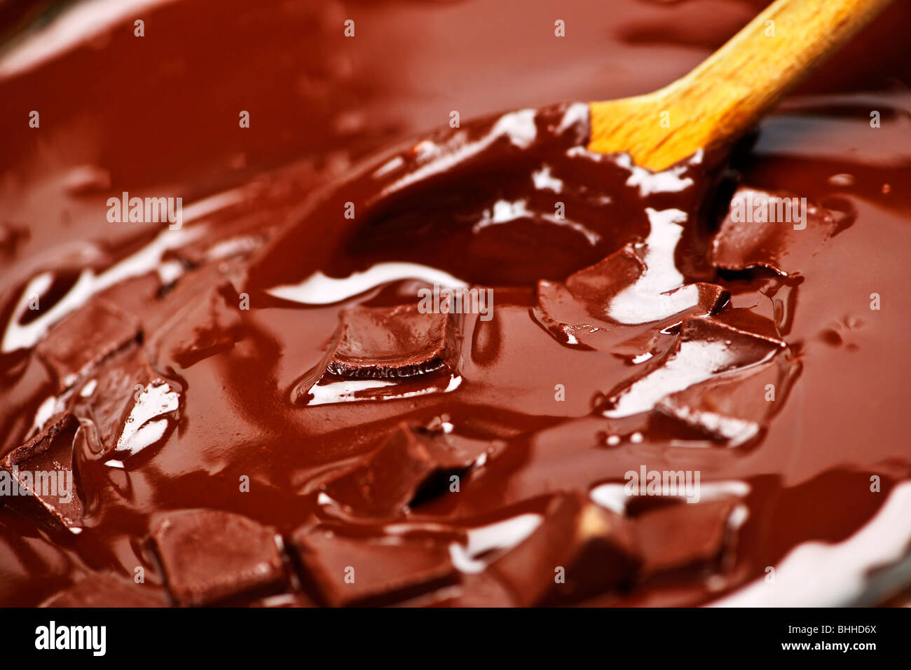 Il cucchiaio di legno di agitazione ricca fusione aggiungete pezzetti di cioccolato Foto Stock
