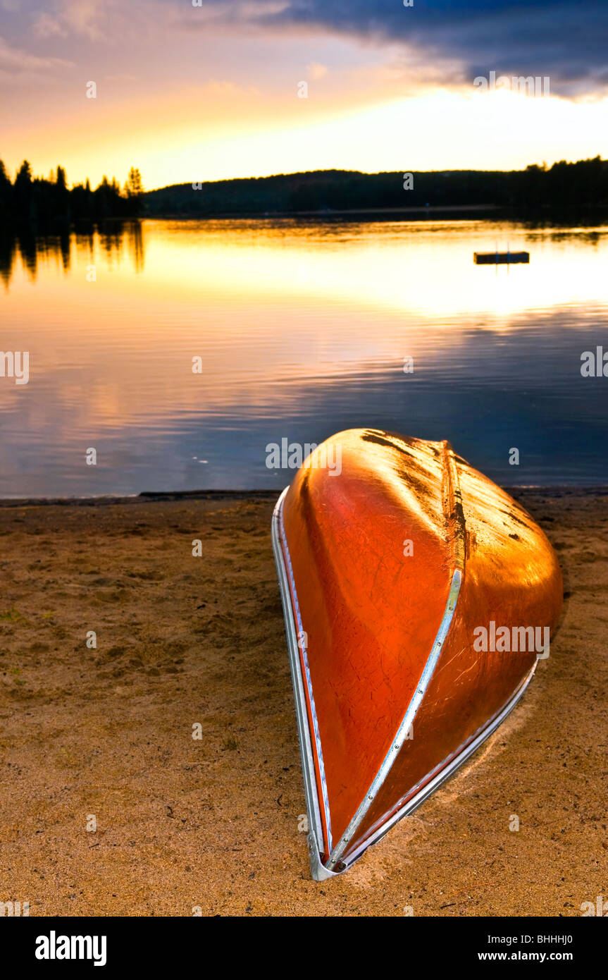 Canoe sulla spiaggia al tramonto sul lago Foto Stock