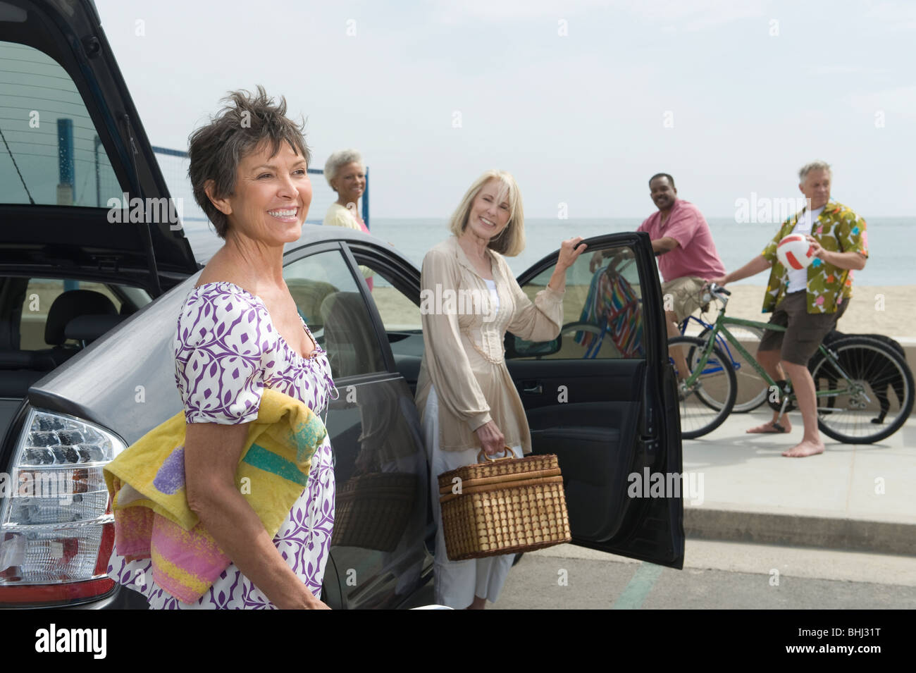 Le donne anziane disimballare auto osservato dagli uomini sulle biciclette Foto Stock