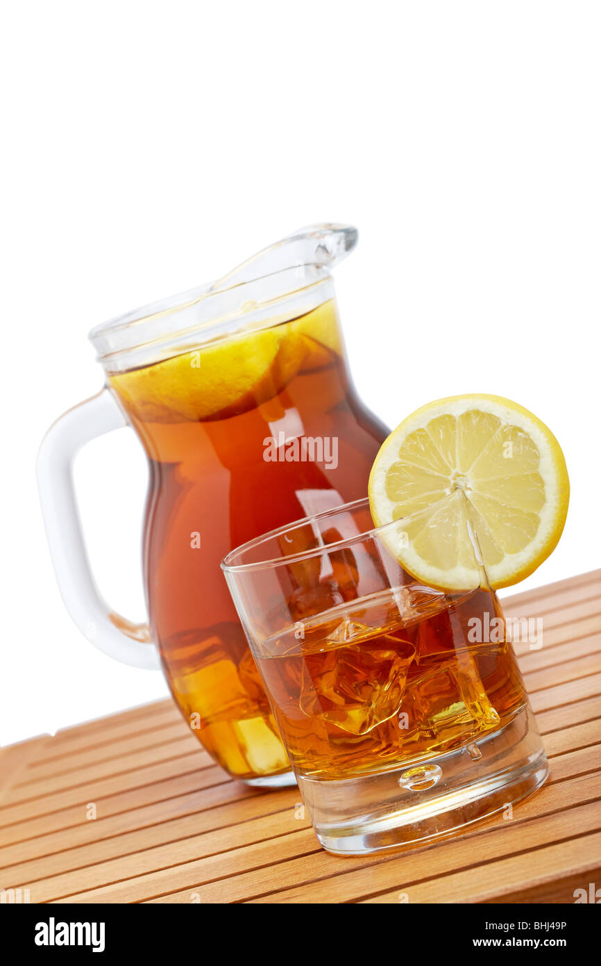 Ice Tea lanciatore e glasss con limone e icecubes su sfondo di legno. Focus sul lato anteriore e la profondità di campo Foto Stock