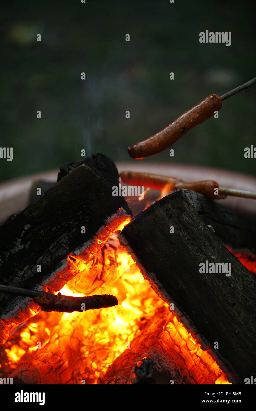 Una salsiccia di essere cucinato a fuoco Foto Stock