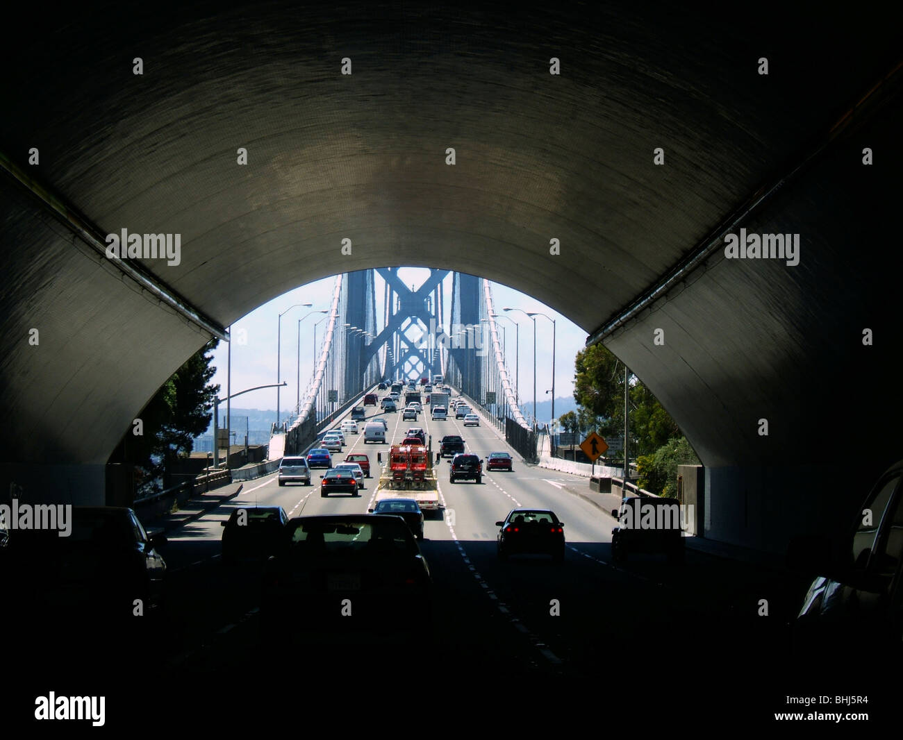 Cars driving su cinque corsie attraverso il tunnel che conduce ad un ponte Foto Stock