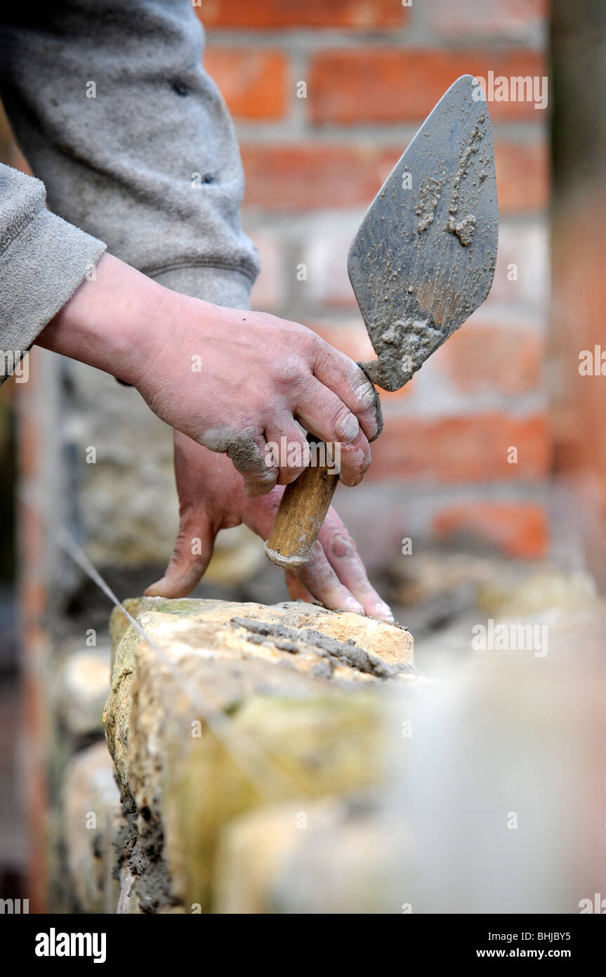 La costruzione di un muro del giardino con cotswold in pietra e malta di cemento nel Regno Unito Foto Stock