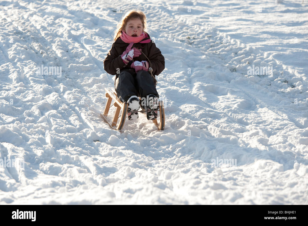 Ragazza giovane di legno tradizionale sled godendo coperta di neve pendenza. Foto Stock