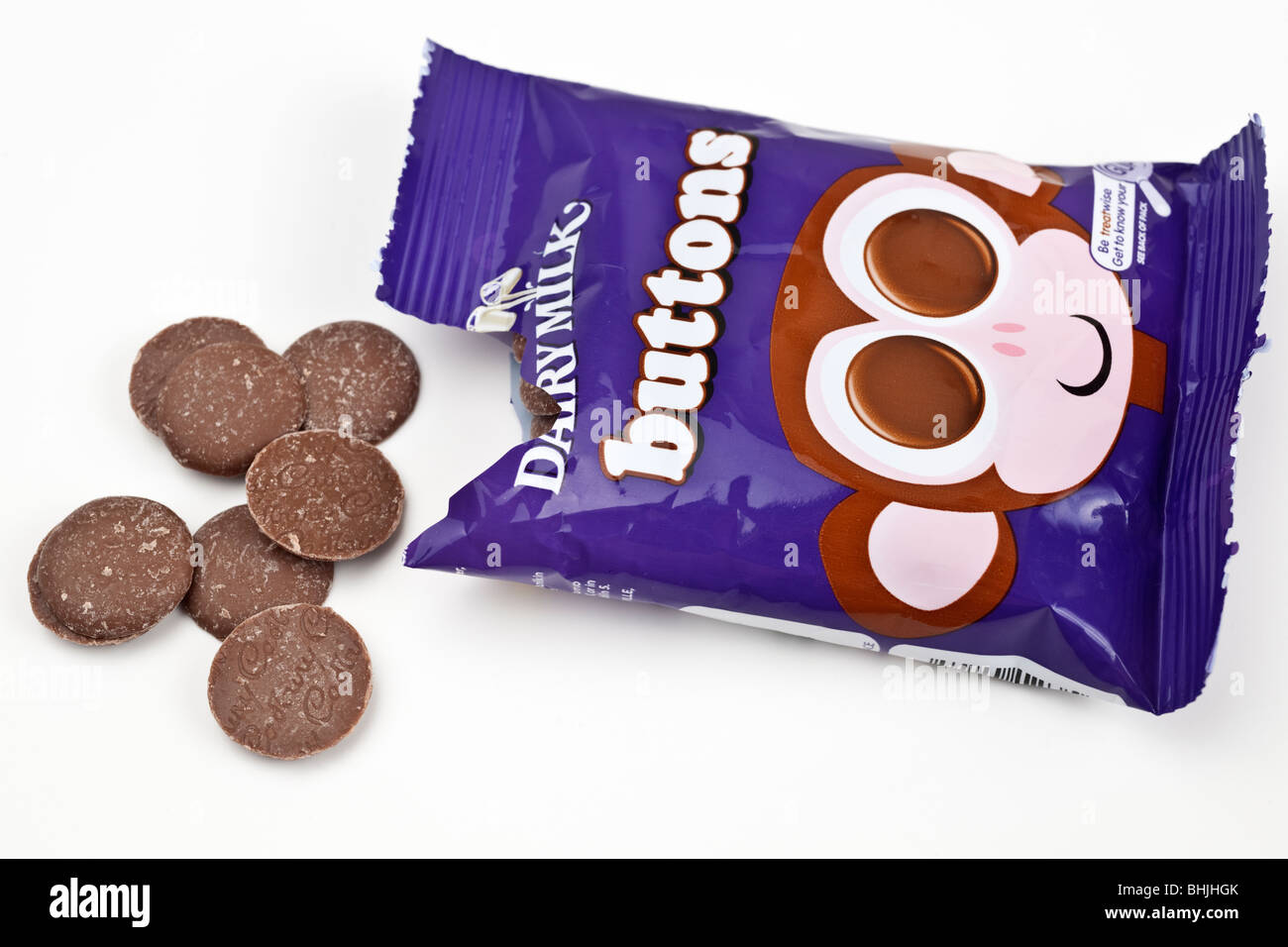 Aprire il sacchetto di Cadburys Dairy milk chocolate sversamento di pulsanti su una superficie bianca Foto Stock