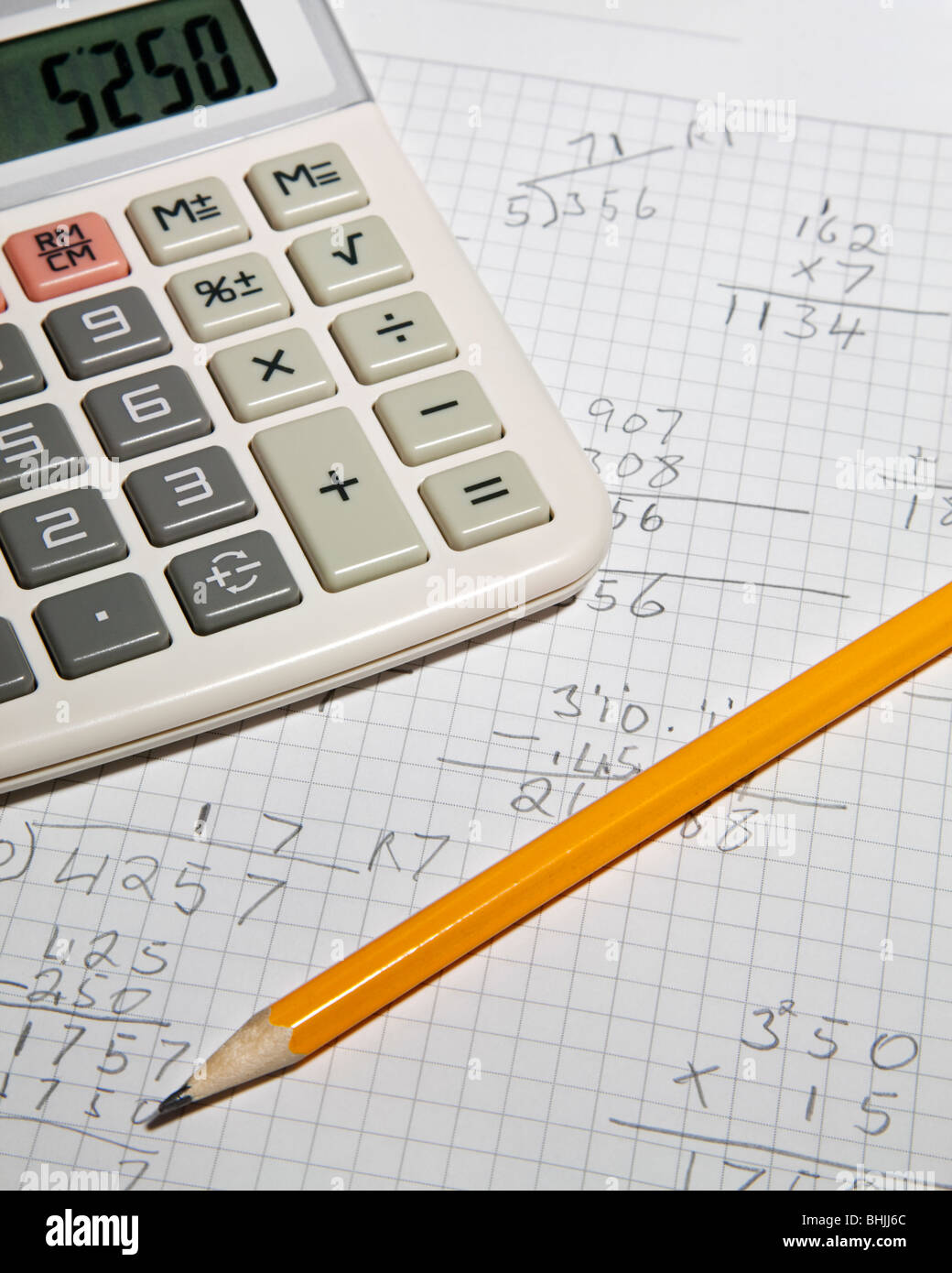 Working out arithmetic sums on a piece of paper with a pencil and calculator. Foto Stock