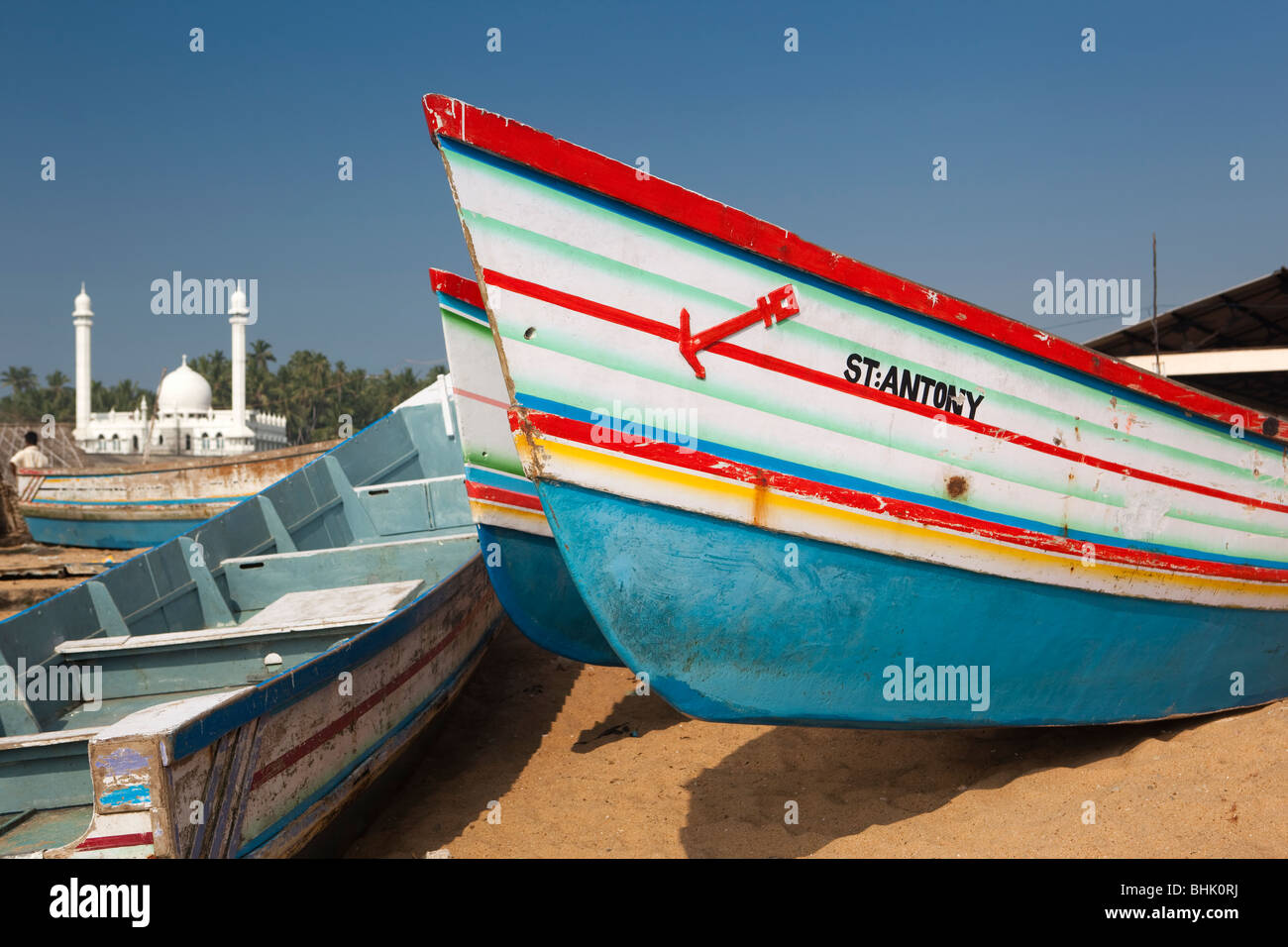India Kerala, Kovalam, villaggio Vizhinjam coloratissime barche di pescatori sulla spiaggia di fronte della nuova moschea Foto Stock