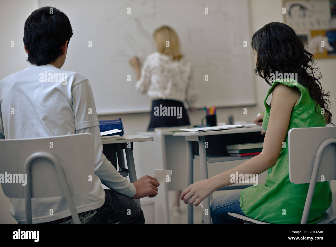 Gli studenti delle scuole superiori che passa gli appunti in classe Foto Stock