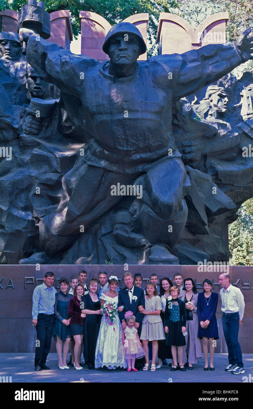 Novelli sposi sotto il Memoriale della Seconda guerra mondiale, Panfilov Park, Almaty, Kazakhstan Foto Stock