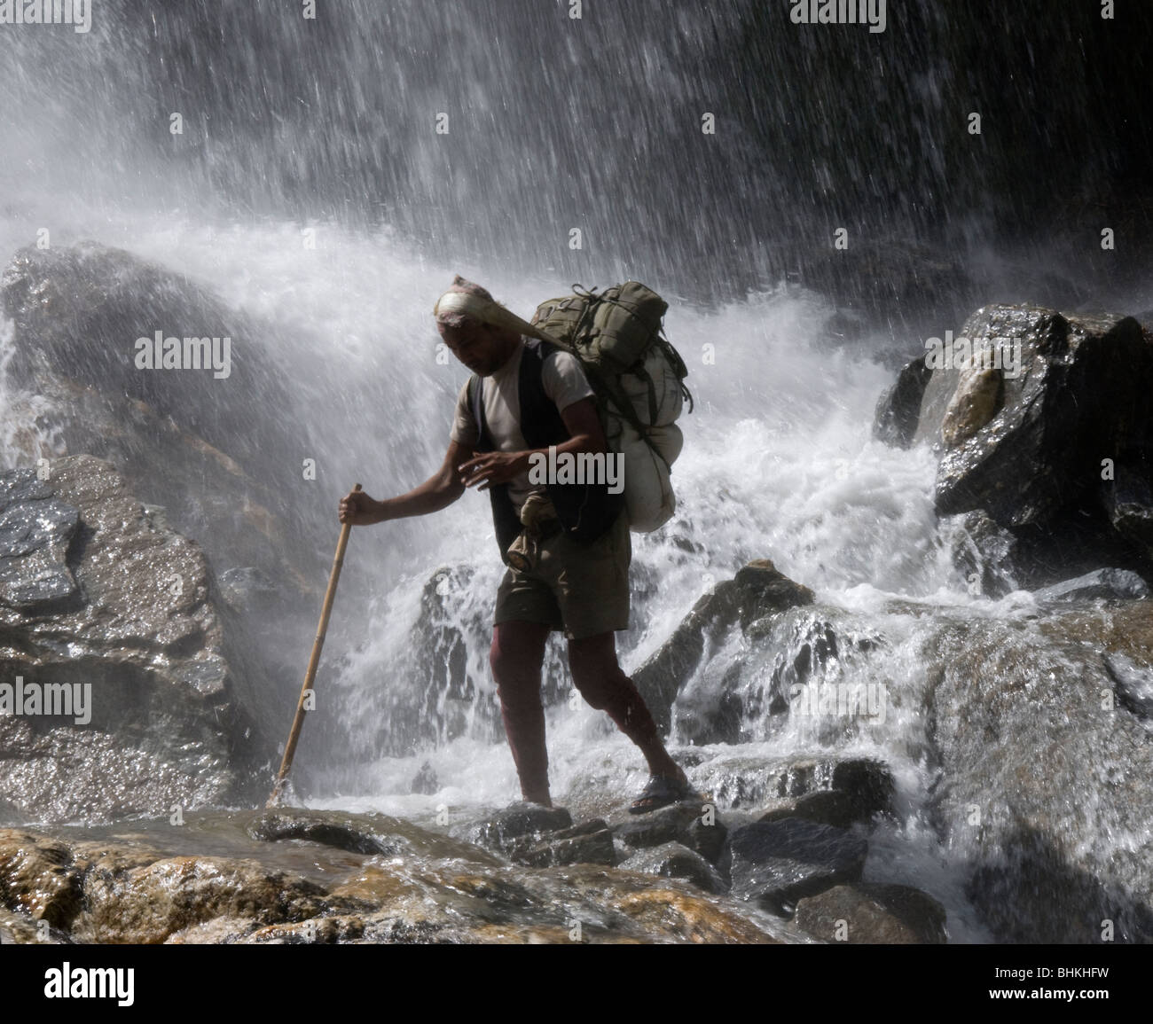 I facchini che trasportano carichi attraverso la cascata, vicino Karte, Circuito di Annapurna, Nepal Foto Stock