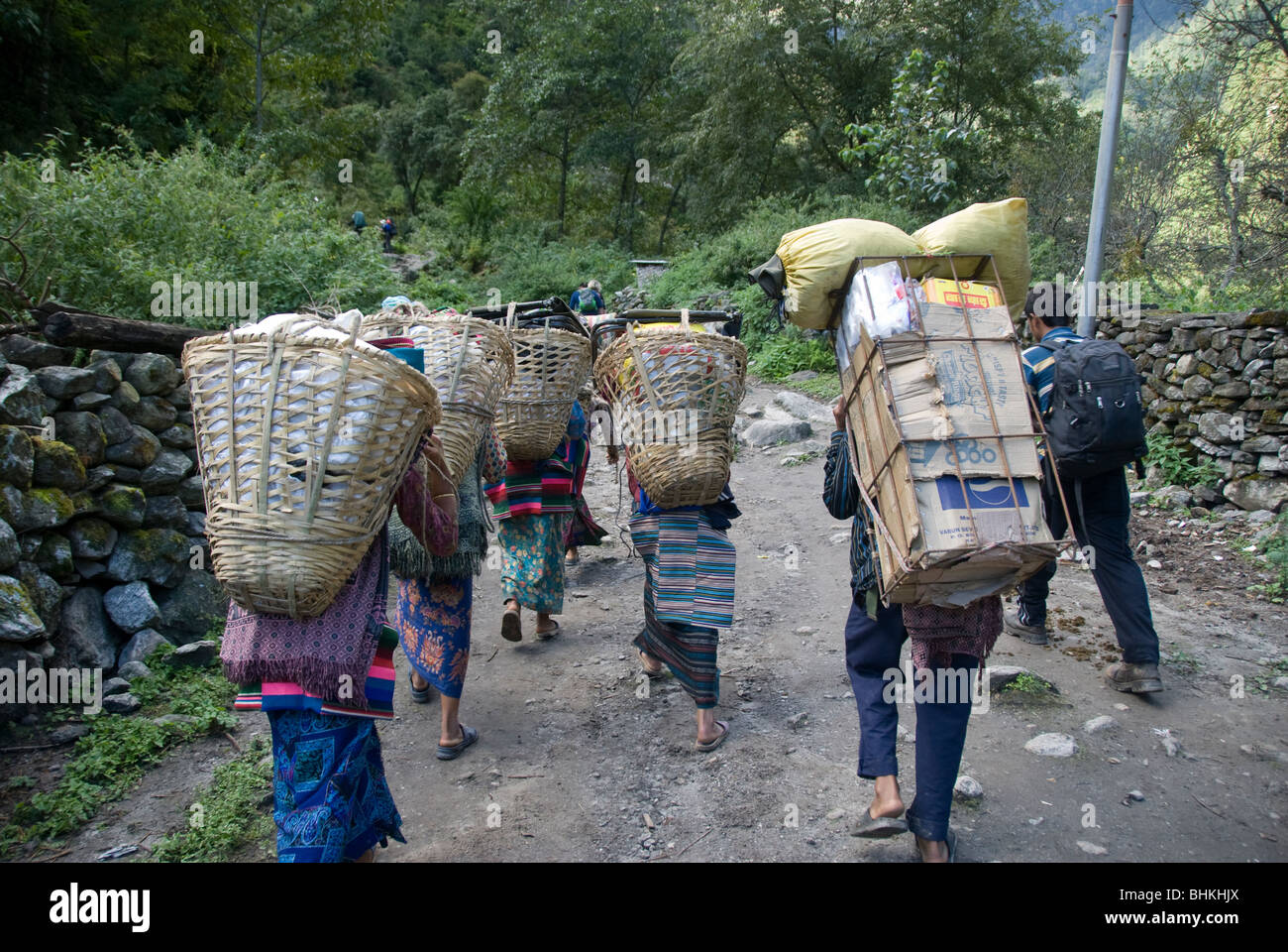 Gli uomini e le donne che trasportano carichi pesanti, vicino Bagarchhap, Circuito di Annapurna, Nepal Foto Stock