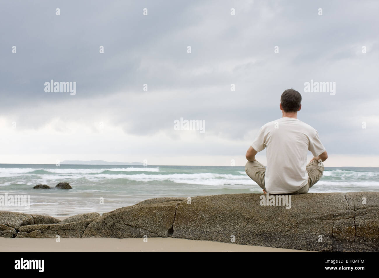L'uomo meditando su una roccia sul mare Foto Stock