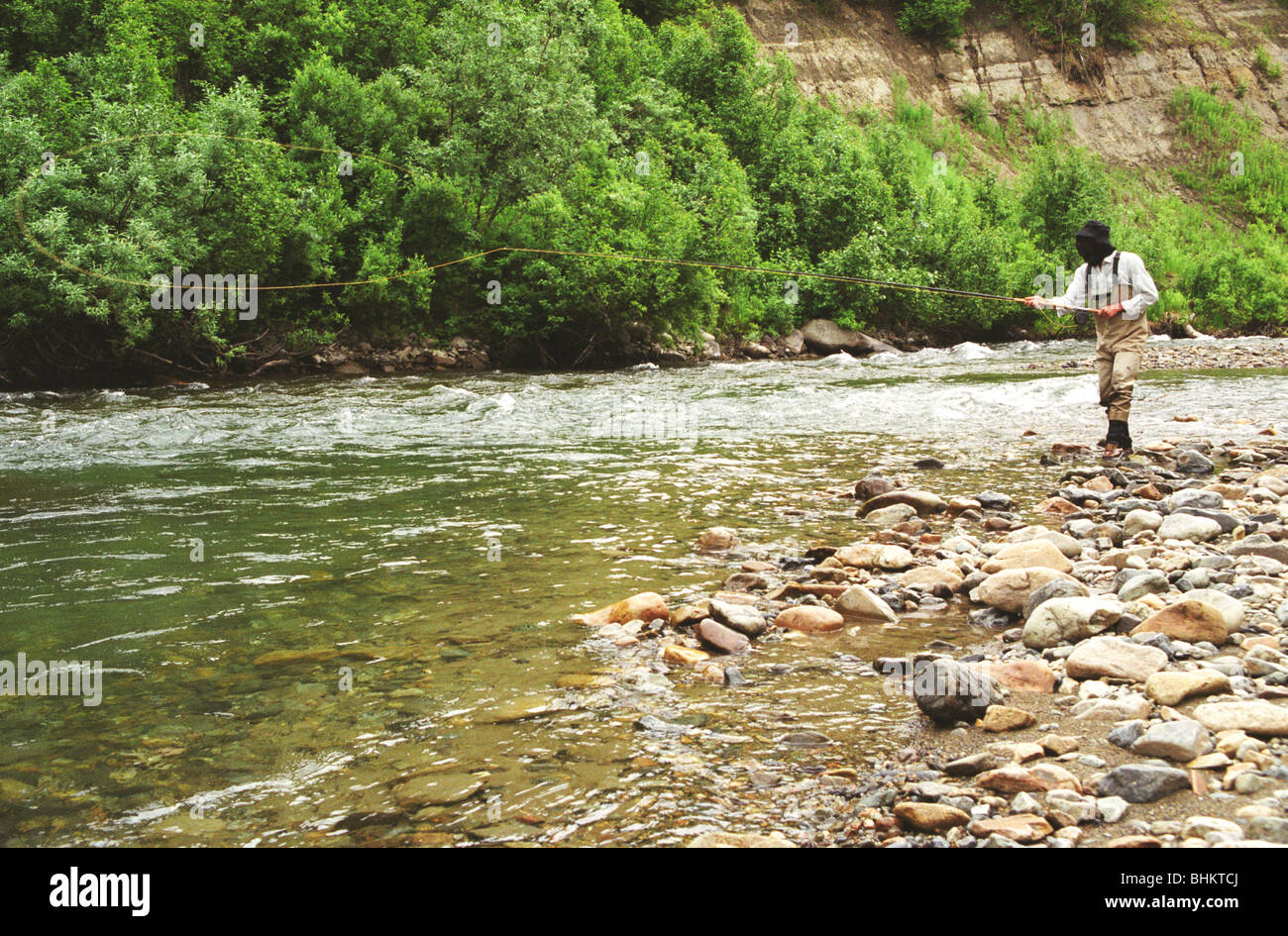 Un flyfisherman colata e indossa un midge net per proteggere contro le punture di insetti Foto Stock