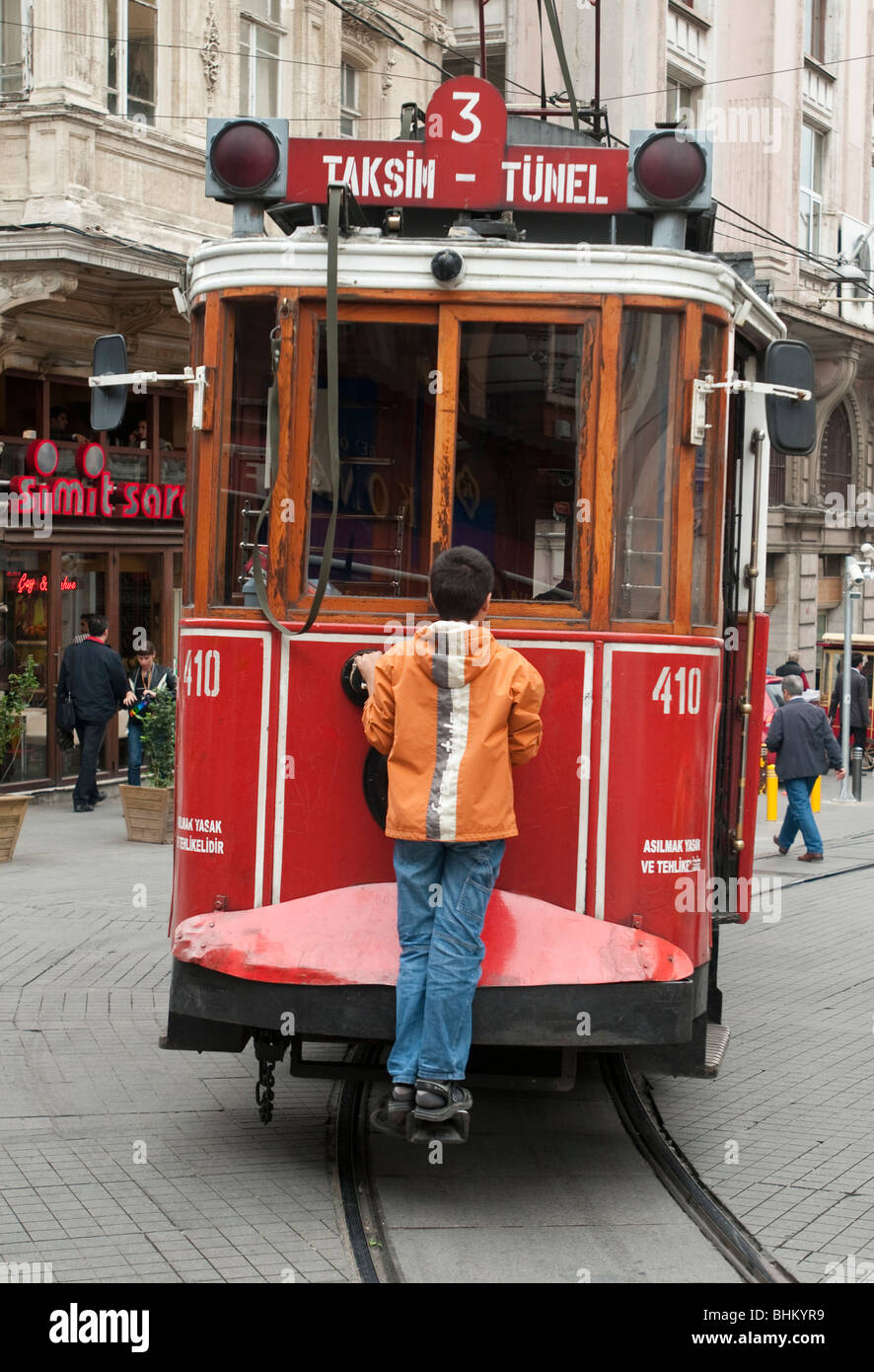 Un ragazzo si blocca su di un tram in Istiklal Caddesi nel Beyoglu area dello shopping di Istanbul Foto Stock