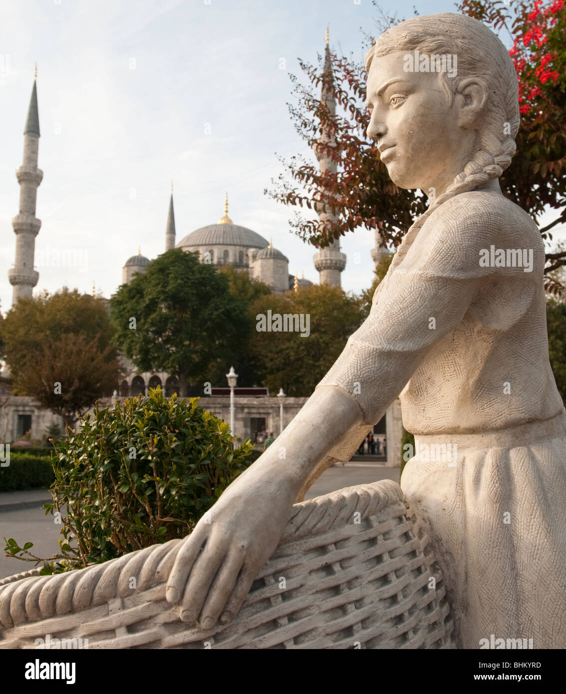 La moschea blu, Istanbul, Turchia fornisce uno sfondo di una statua di una giovane donna che mantiene un cestello i Foto Stock