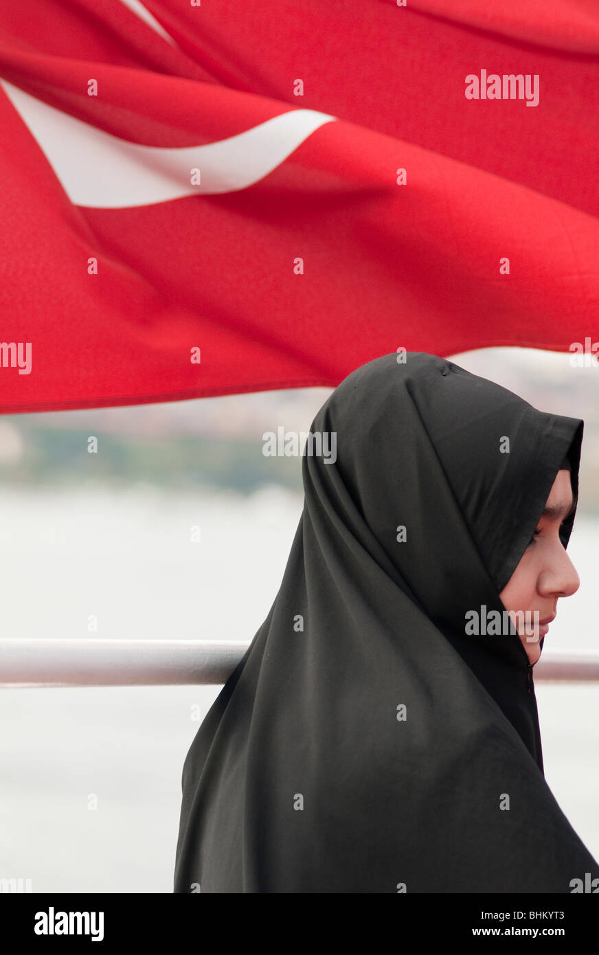 Una giovane donna che indossa un hijab sorge di fronte al Bagno Turco bandiera nazionale Foto Stock