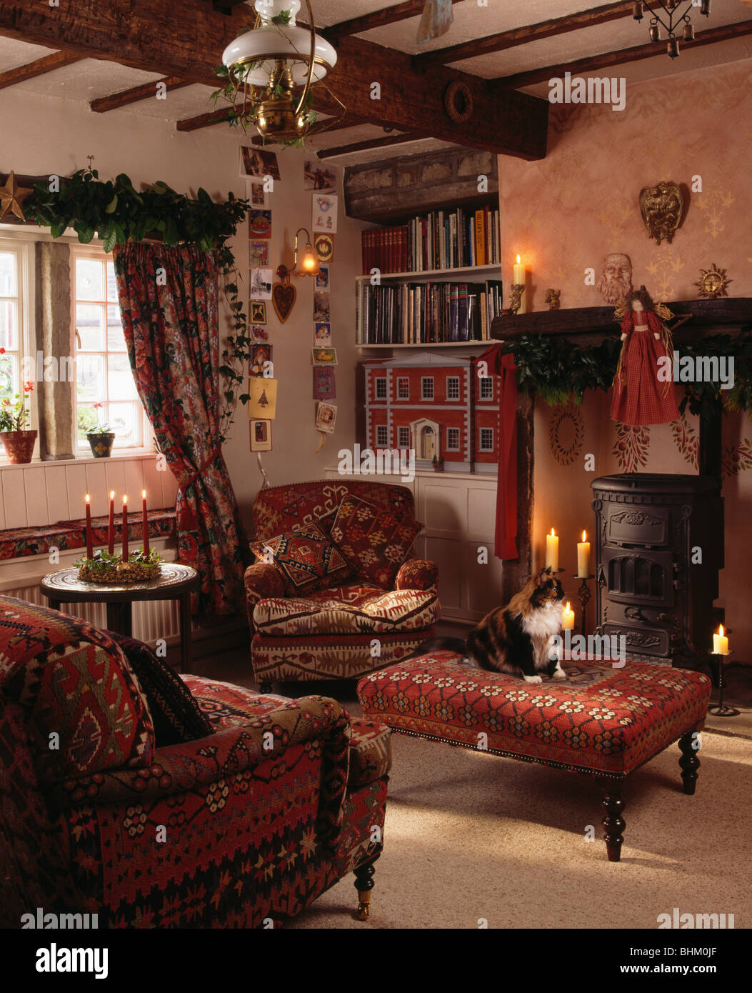 Arazzo rosso-Sgabello imbottito e confortevole poltrona accanto al caminetto nel cottage soggiorno decorato per il Natale Foto Stock