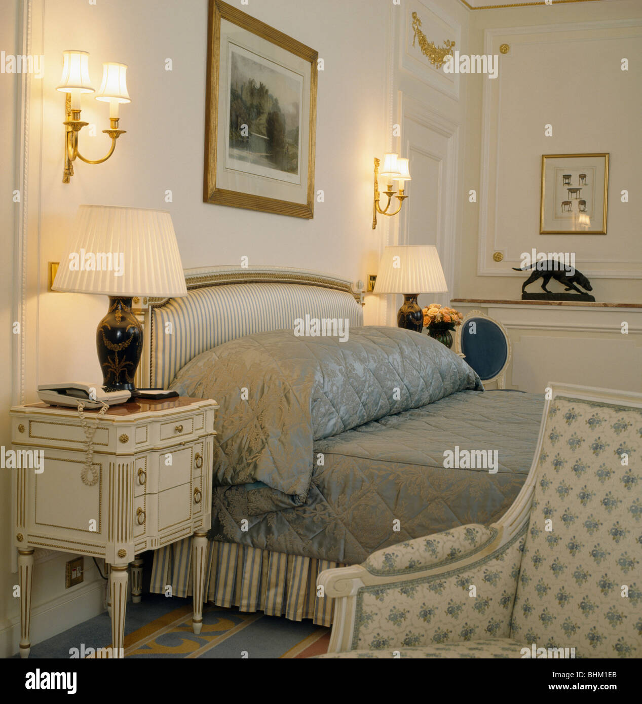 Lampade illuminate sui comodini su entrambi i lati del letto imbottito con grigio cuscino imbottito e trapuntato e copriletto townhouse in camera da letto Foto Stock