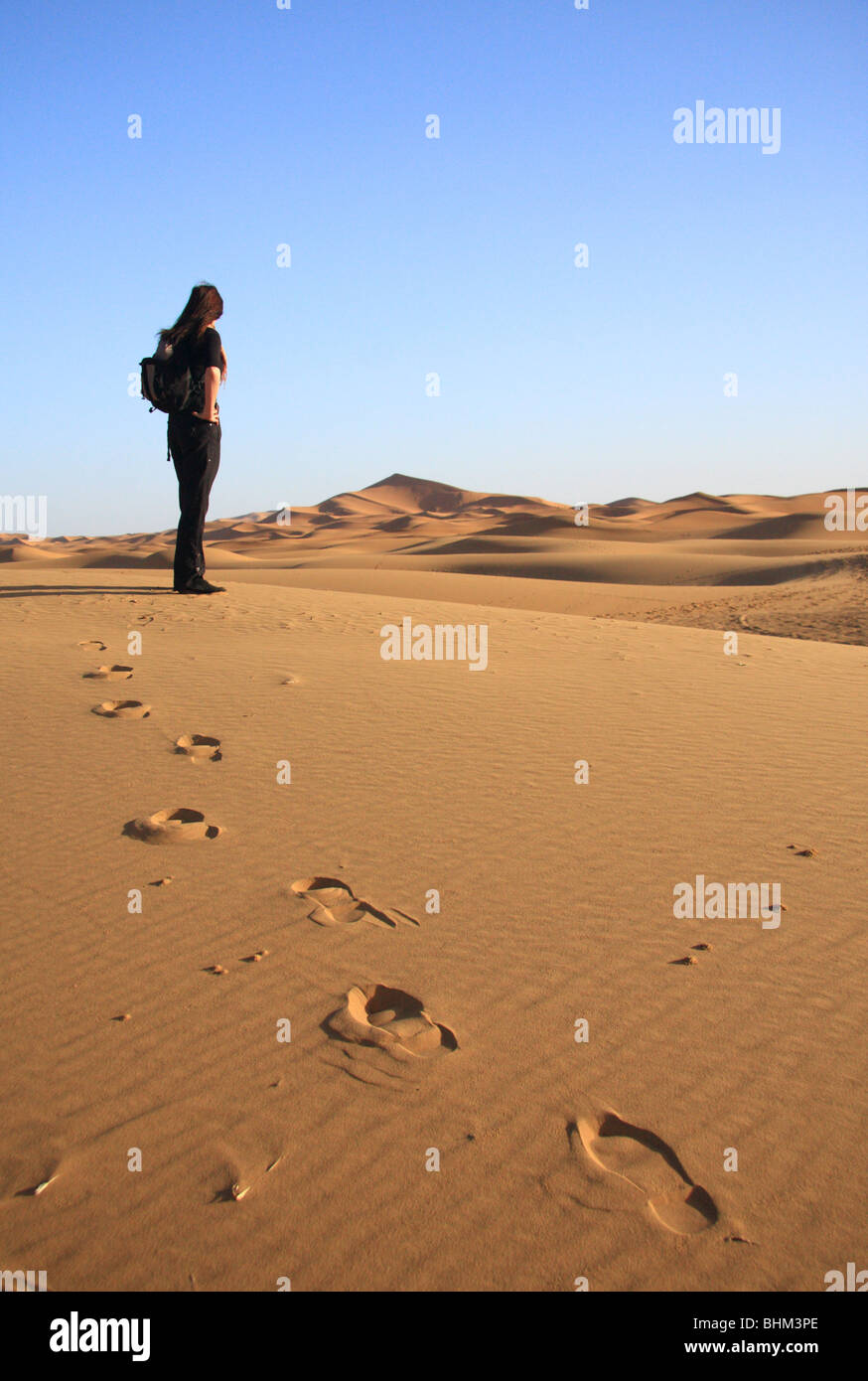 Turista femminile guarda fuori attraverso la Erg Chebbi dune di sabbia nel deserto del Sahara vicino a Merzouga, Marocco, Africa del Nord Foto Stock