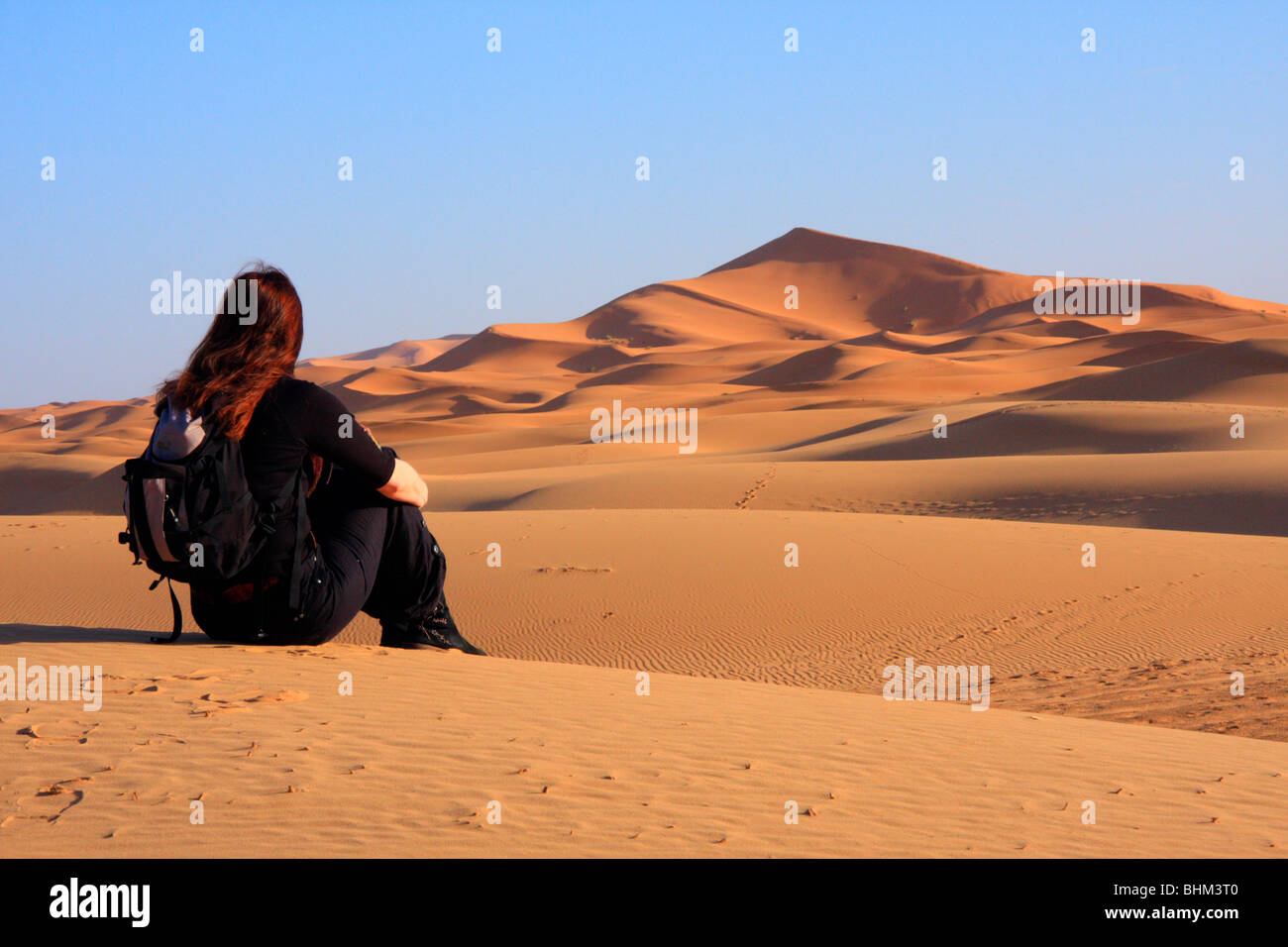 Turisti femmina guarda fuori attraverso la Erg Chebbi snad dune nel deserto del Sahara vicino a Merzouga, Marocco Foto Stock