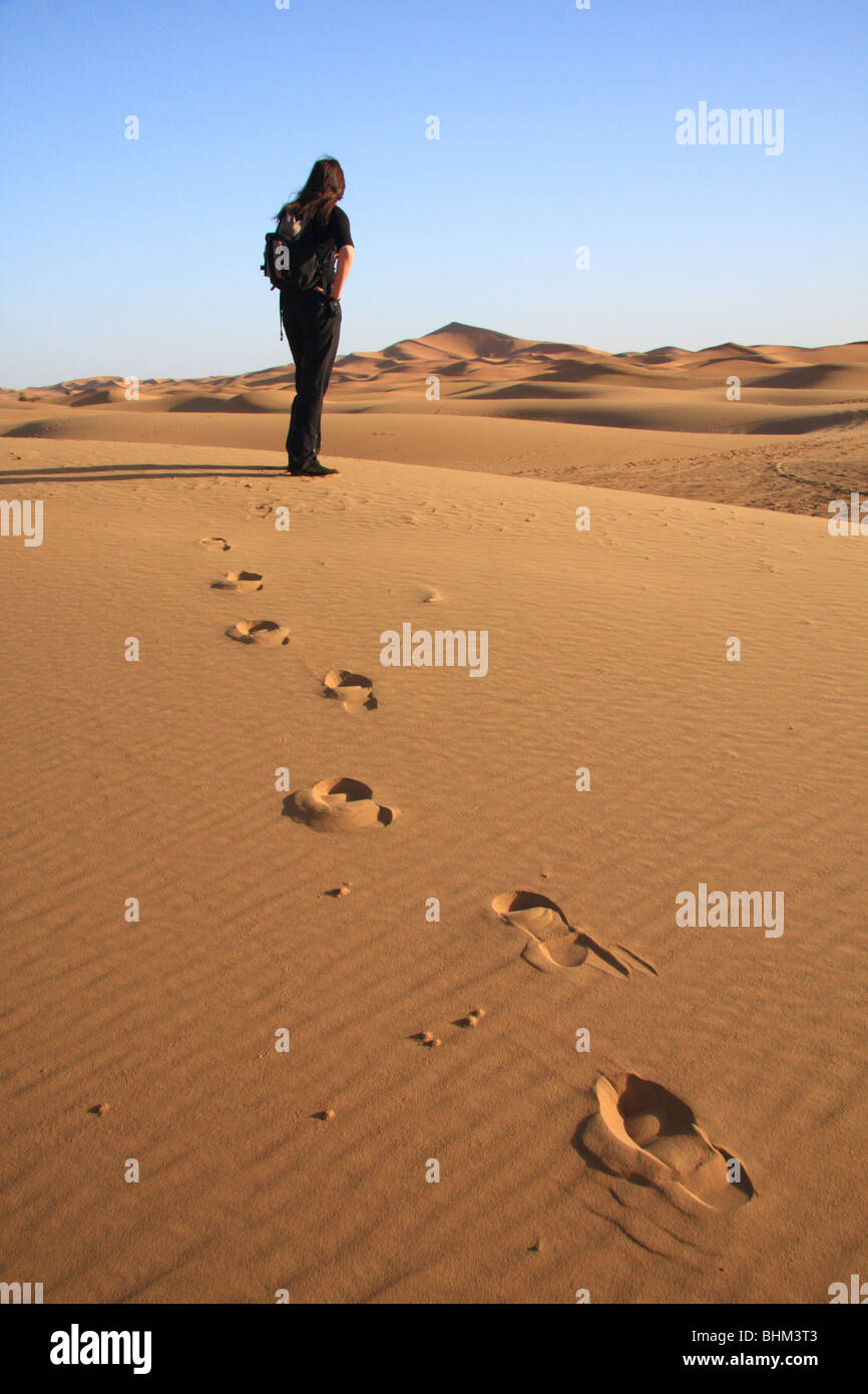 Turista femminile guarda fuori attraverso la Erg Chebbi dune di sabbia nel deserto del Sahara vicino a Merzouga, Marocco Foto Stock