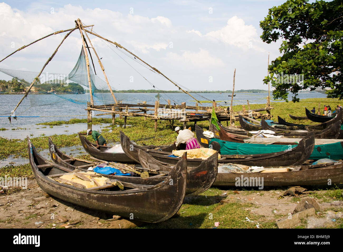 Cinese di reti da pesca, barche e pescatori sulla spiaggia di Fort Cochin, Cochin, Kerala, India Foto Stock