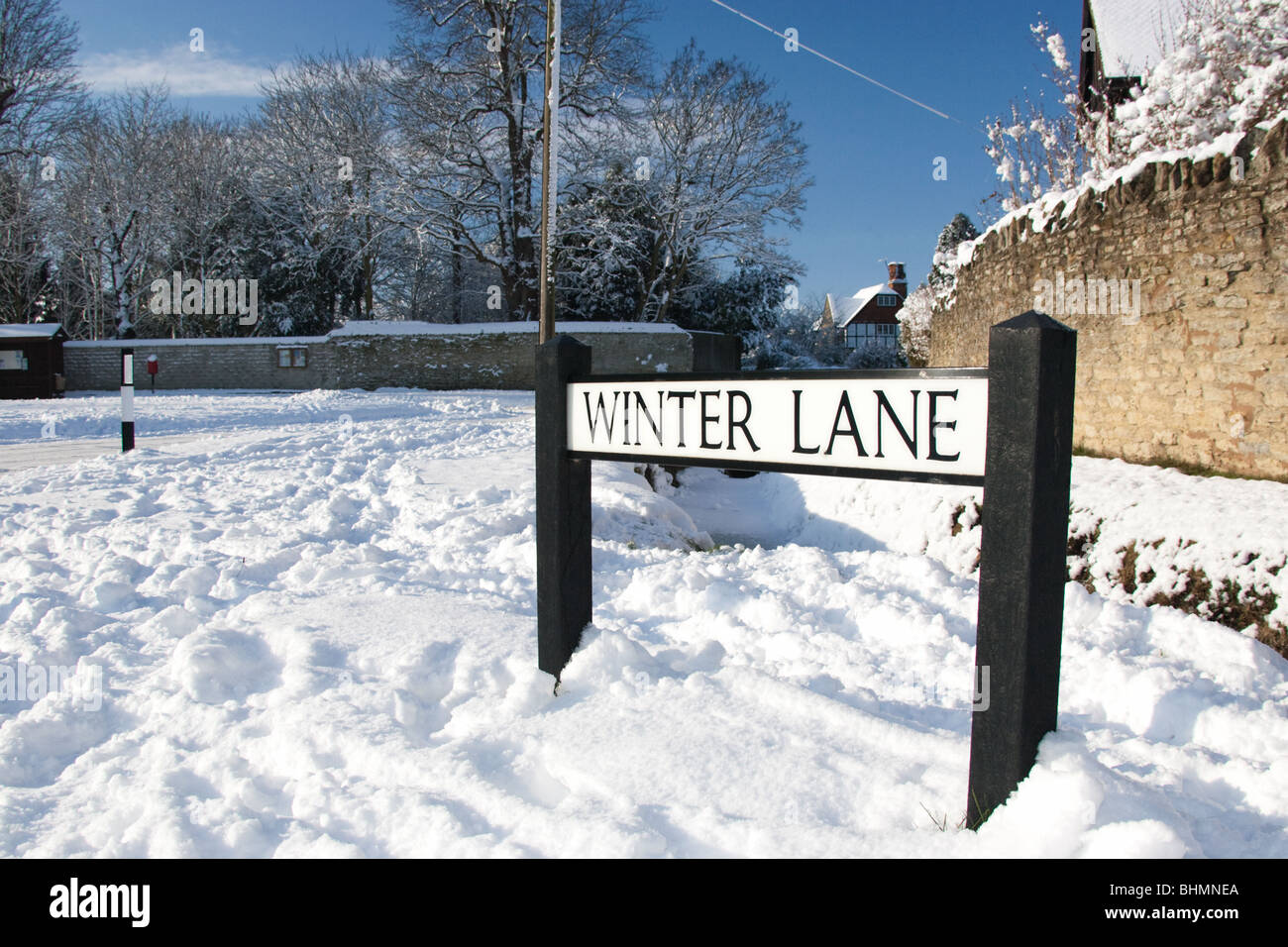 Strada segno 'inverno lane' (west hanney, oxfordshire, Regno Unito) mostrato nella neve profonda contro il blu intenso del cielo e muro di pietra dello sfondo. Foto Stock