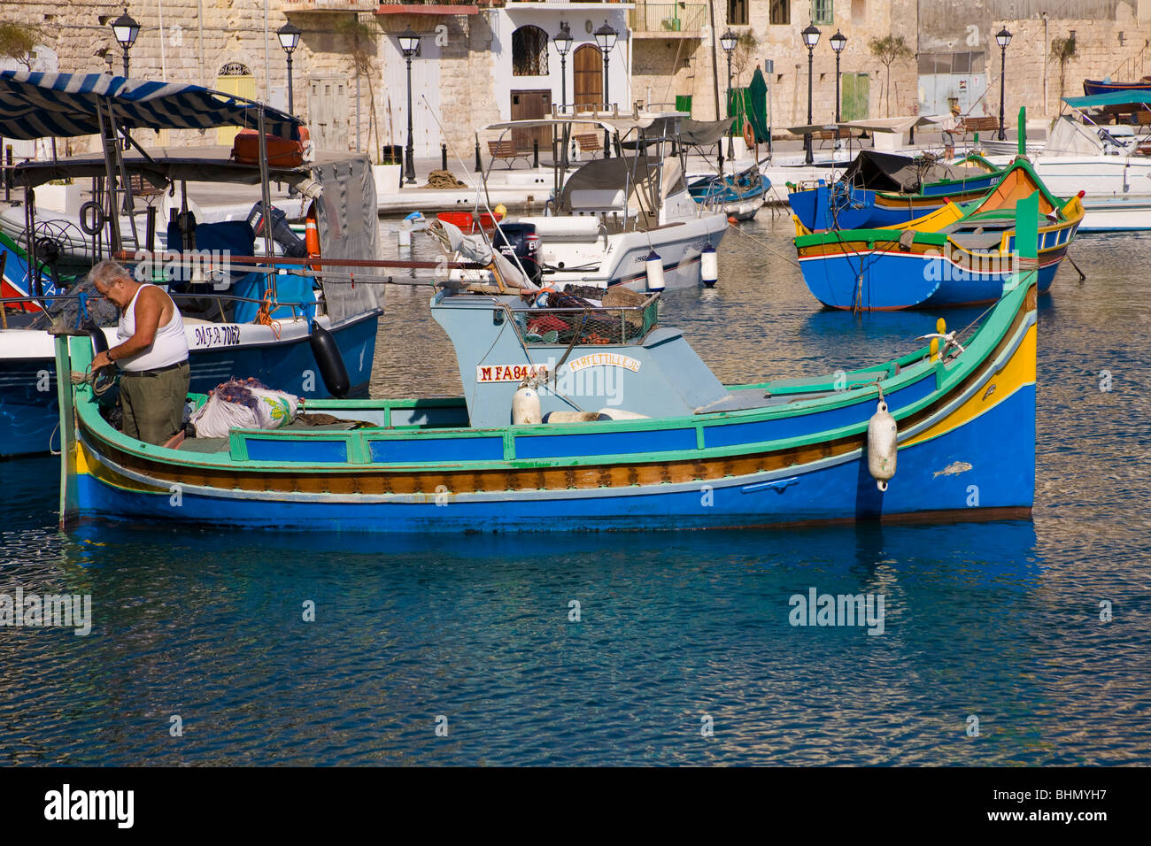 Dipinto luminosamente Luzzu pesca barca ormeggiata in Saint Julian's Harbour, Spinola Bay, Saint Julian, Malta Foto Stock