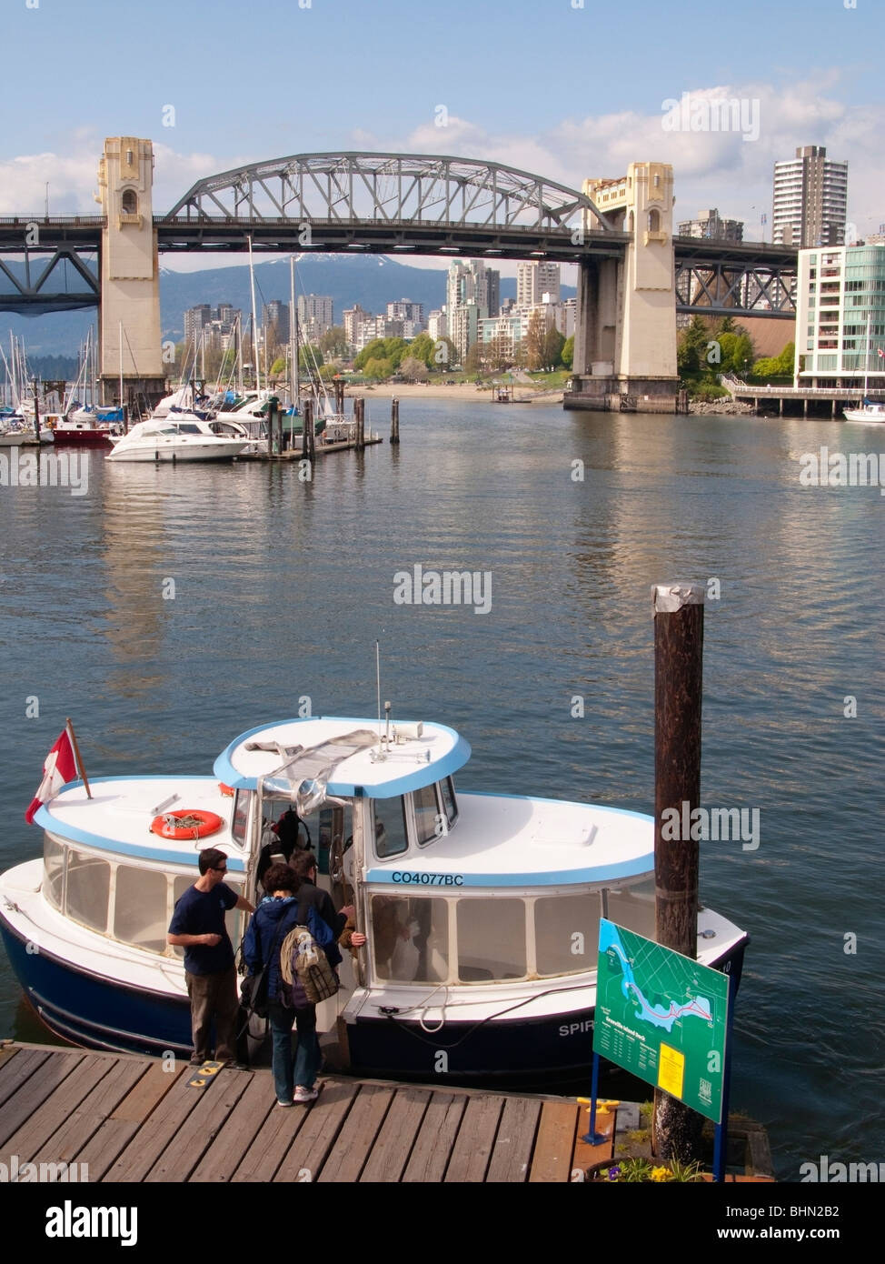 I passeggeri di salire a bordo di un False Creek Ferries acqua taxi a Granville Island, Burrard Street Bridge al di là, Vancouver, BC, Canada Foto Stock