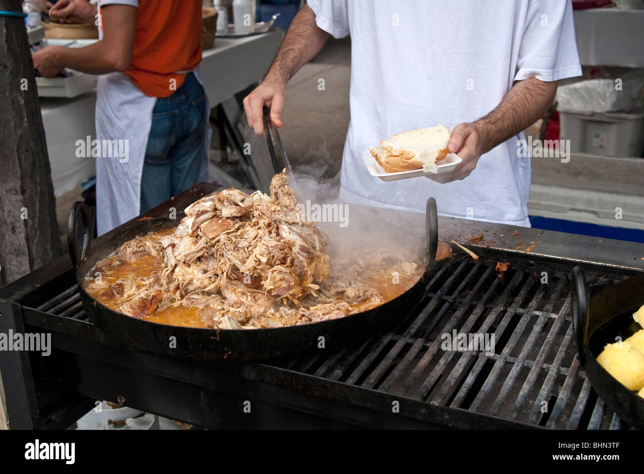 L'uomo la preparazione di estratto di carne di maiale a sandwich un street fair, Toronto, Canada Foto Stock