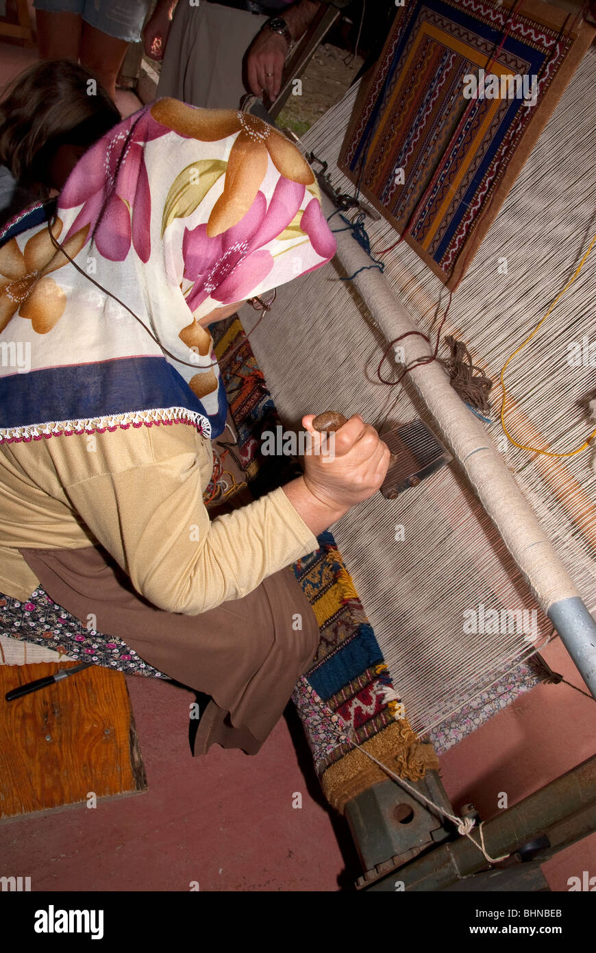 Bagno turco donna dimostrando la tessitura dei tappeti per turisti britannici Foto Stock