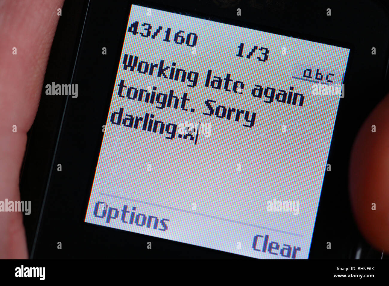 Messaggio di testo su un telefono cellulare affermando che "lavora fino a tardi stasera. Siamo spiacenti darling.x' Foto Stock