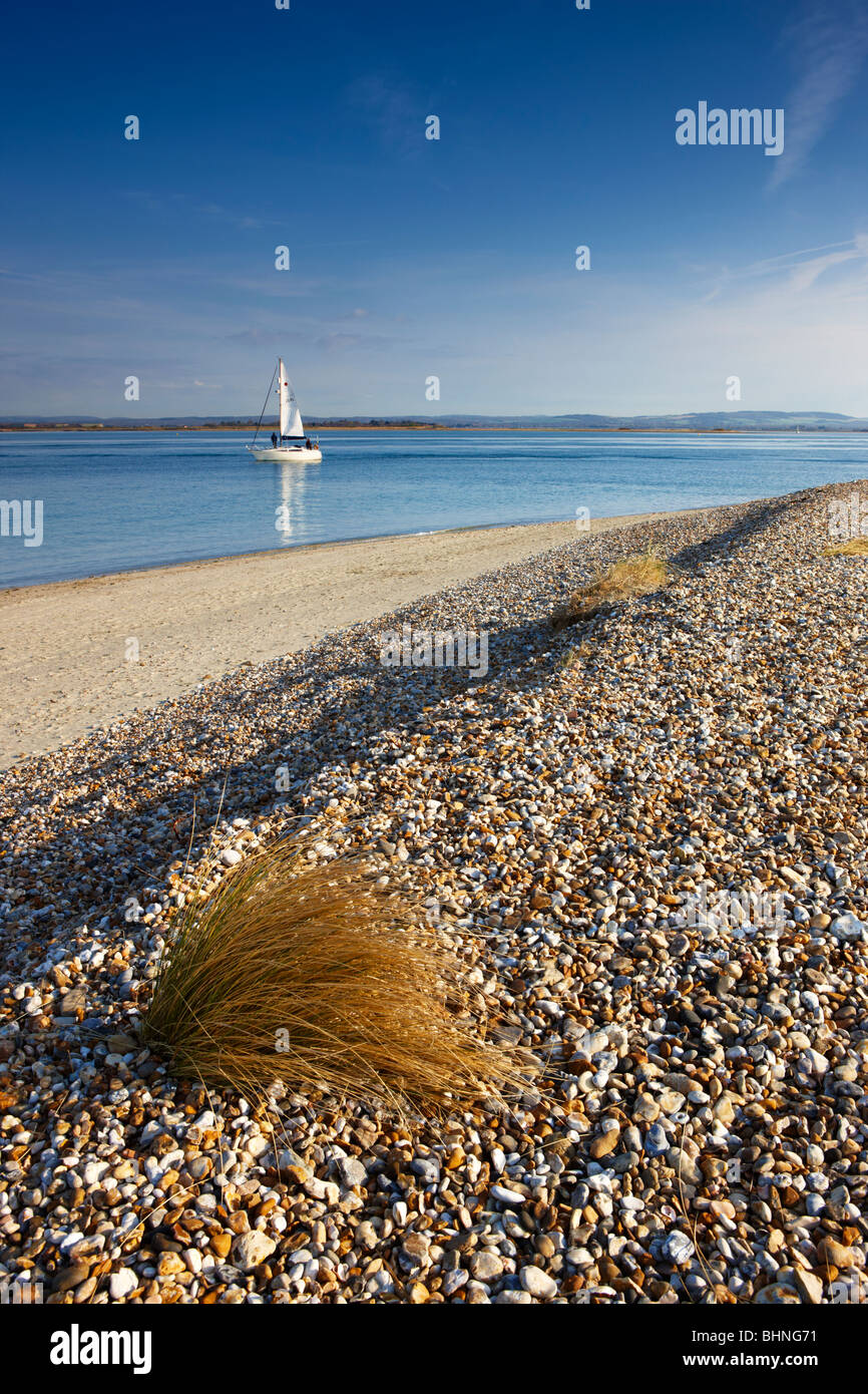 Una solitaria barca a vela vele per mare, testata est, West Wittering Foto Stock