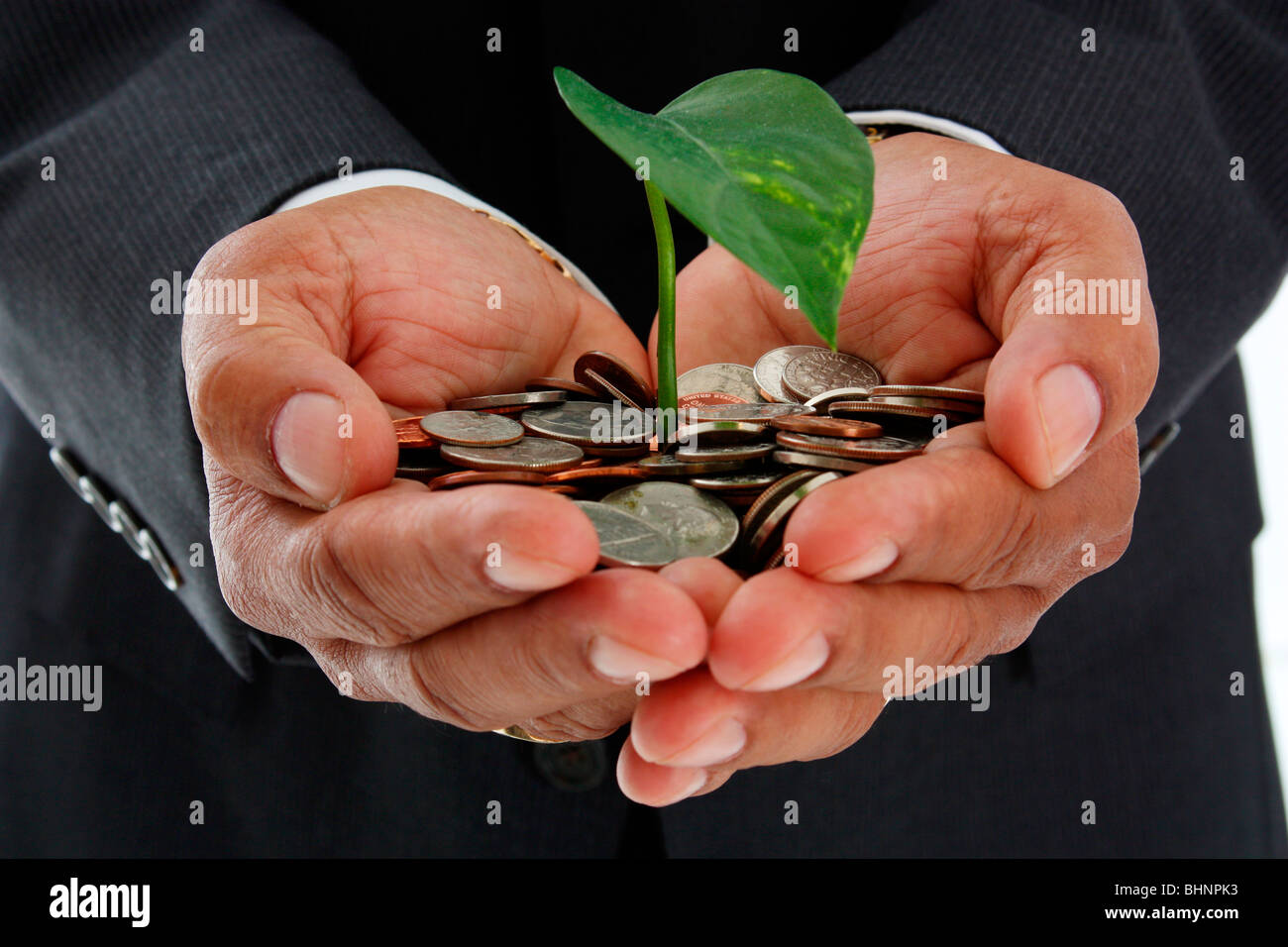 Uomo ispanico tenendo un impianto in un mucchio di soldi Foto Stock