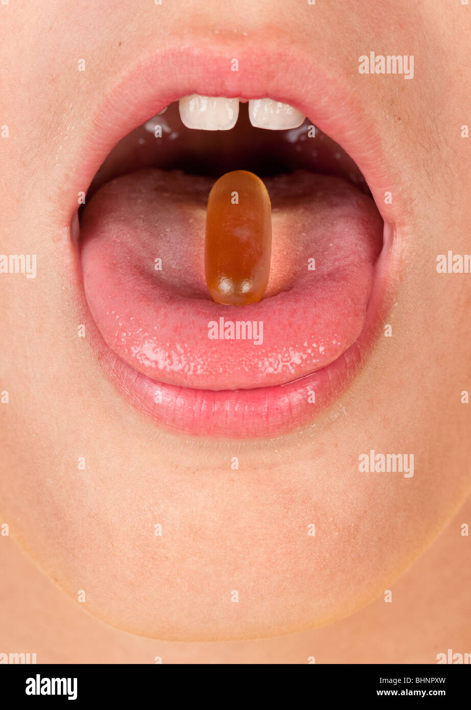 Ragazzi in bocca con una pillola o una capsula sulla linguetta Foto Stock