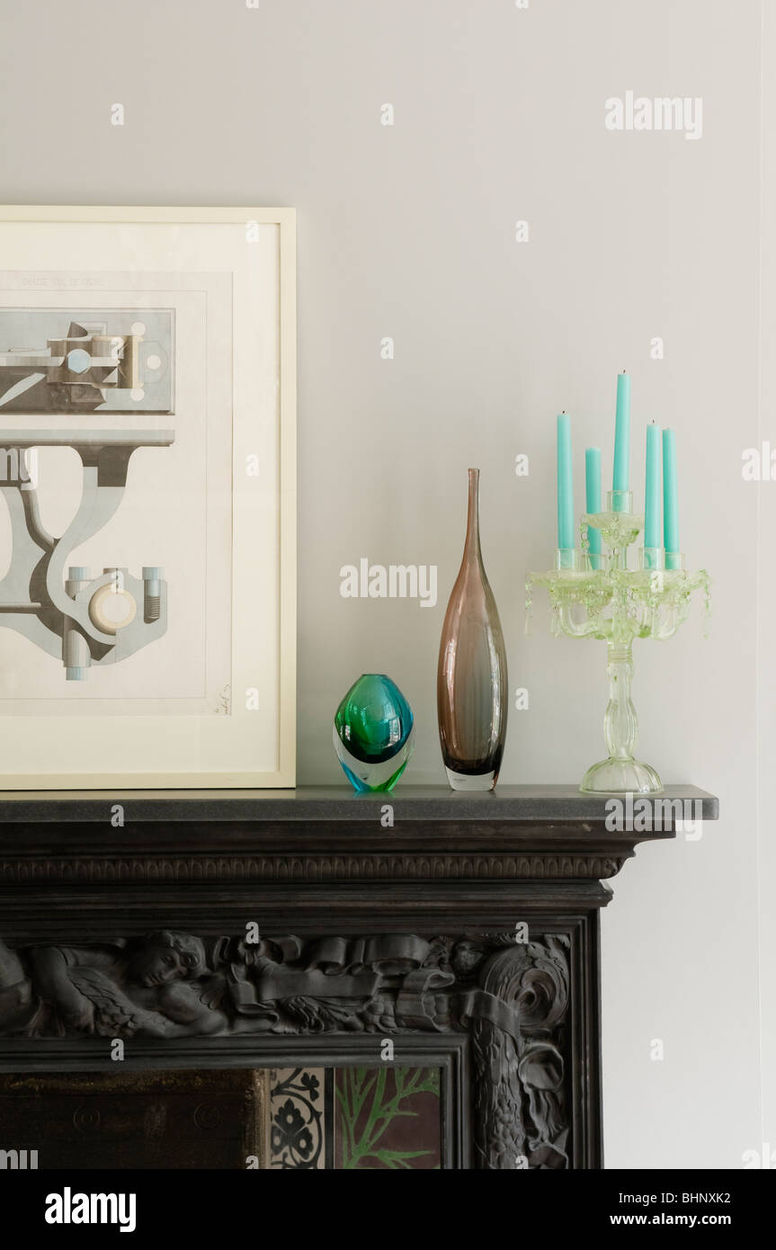 Artwork, vetreria e candelabri sulla mantelpiece intagliato Foto Stock