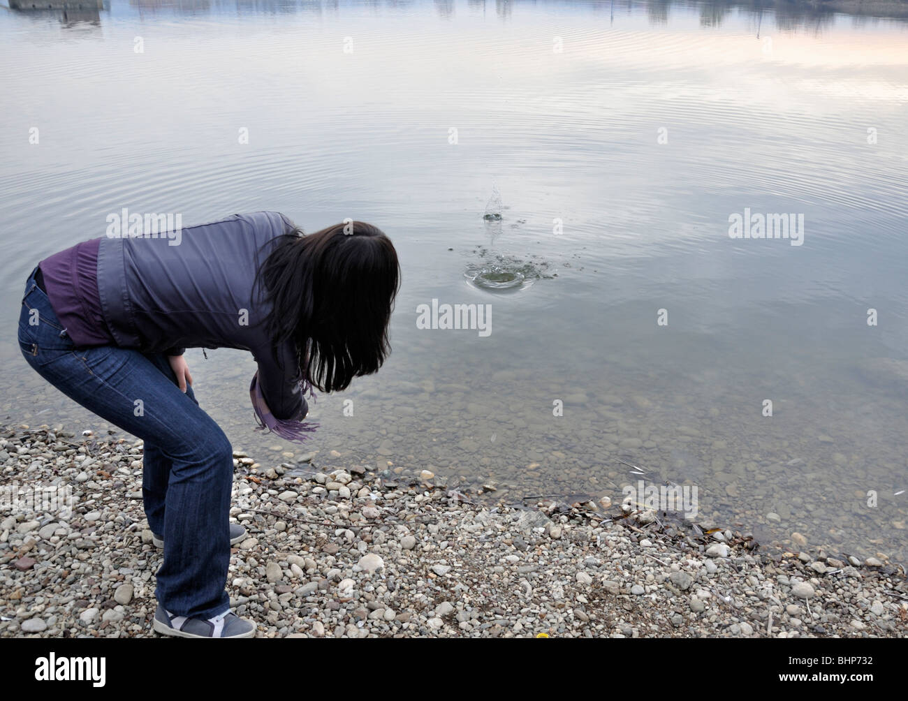 Donna pietra di salto nel lago Foto Stock