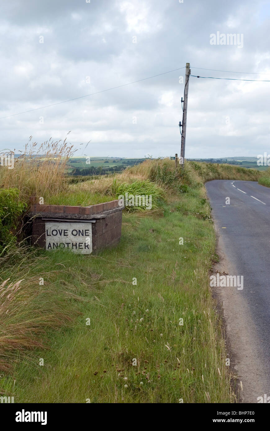 Una strana lato strada segno con le parole "amore gli uni per gli altri", Cornwall, Regno Unito Foto Stock