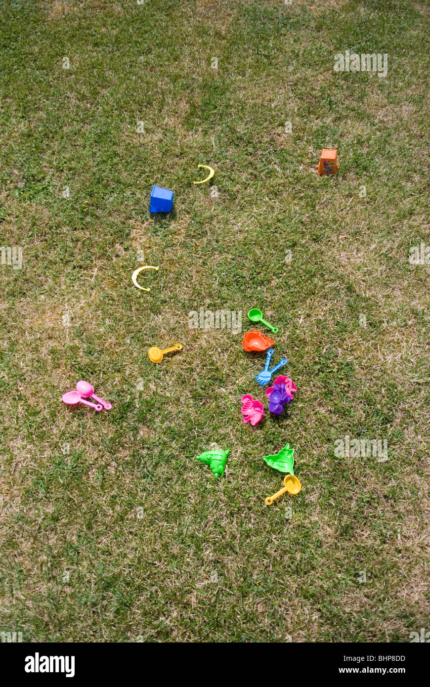 Un assortimento delle colorate bambini giocattoli di plastica giacciono sparsi su un prato in un giardino privato Foto Stock