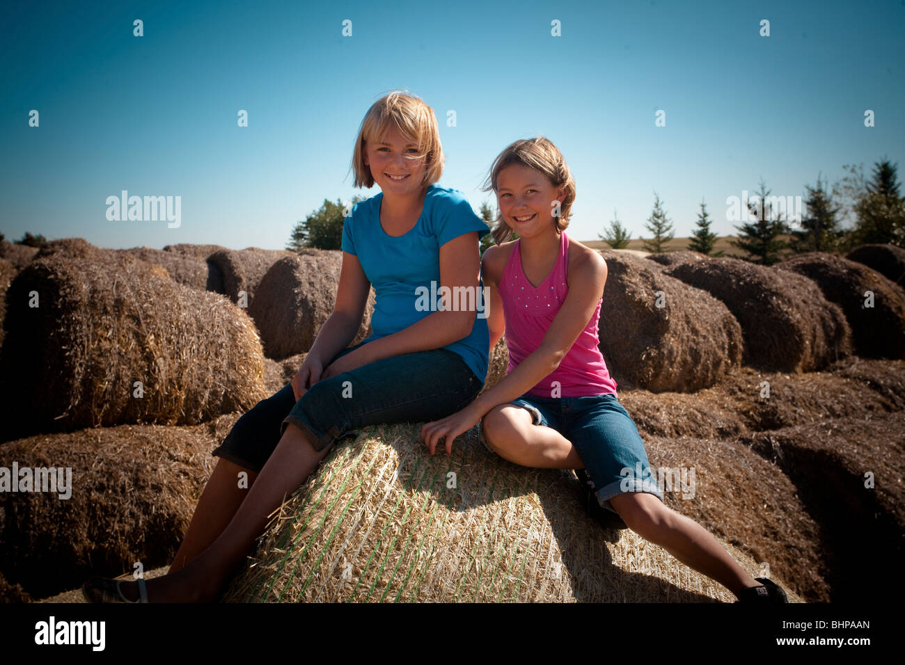 Due ragazze, 10 e 12, sede di balle di paglia; Redvers, Saskatchewan, Canada Foto Stock