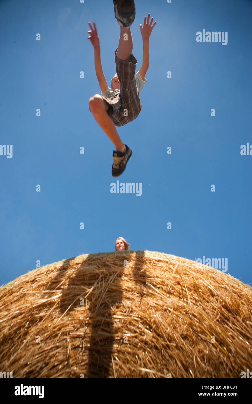 Ragazzo (12) Mid saltare in balle di paglia; Redvers, Saskatchewan, Canada Foto Stock