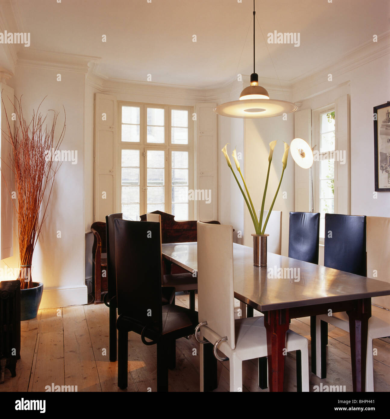 Ciondolo di luce sopra la tabella in legno di quercia e in bianco e nero e sedie di pelle bianca in bianca e moderna sala da pranzo Foto Stock