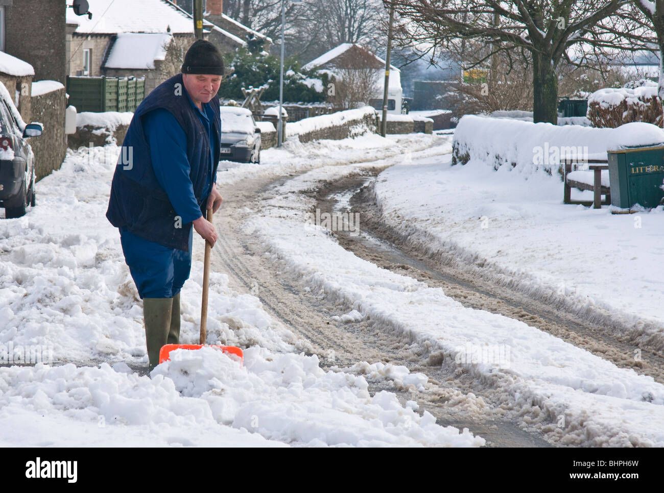 L'uomo la rimozione di neve da una strada attraverso un villaggio. Foto Stock