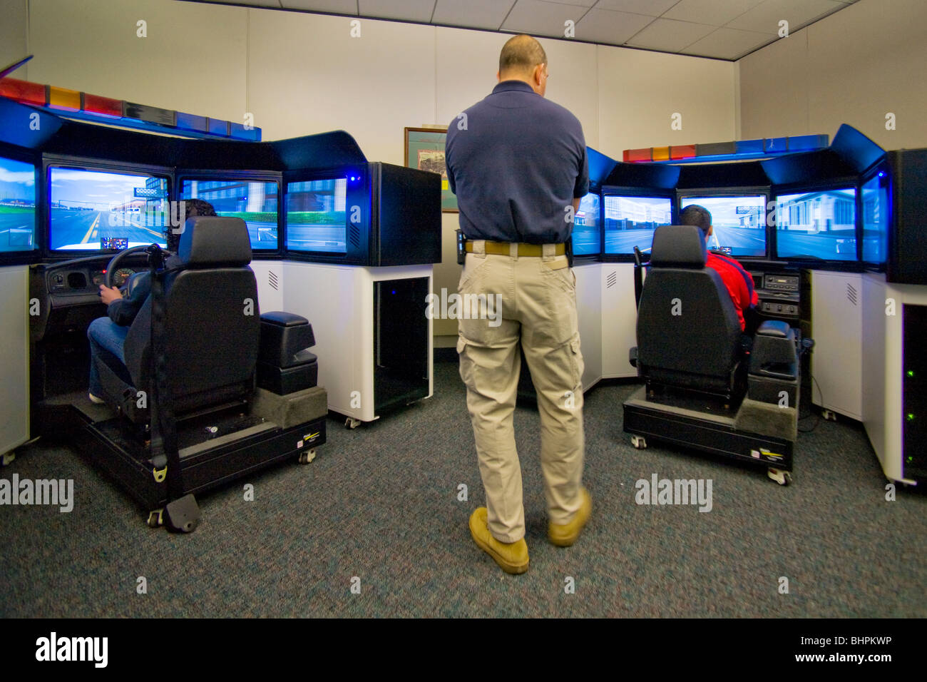 In qualità di istruttore di orologi, funzionari di polizia pratica guida ad alta velocità delle competenze a pattuglia di simulatori con real ruote sterzanti. Foto Stock