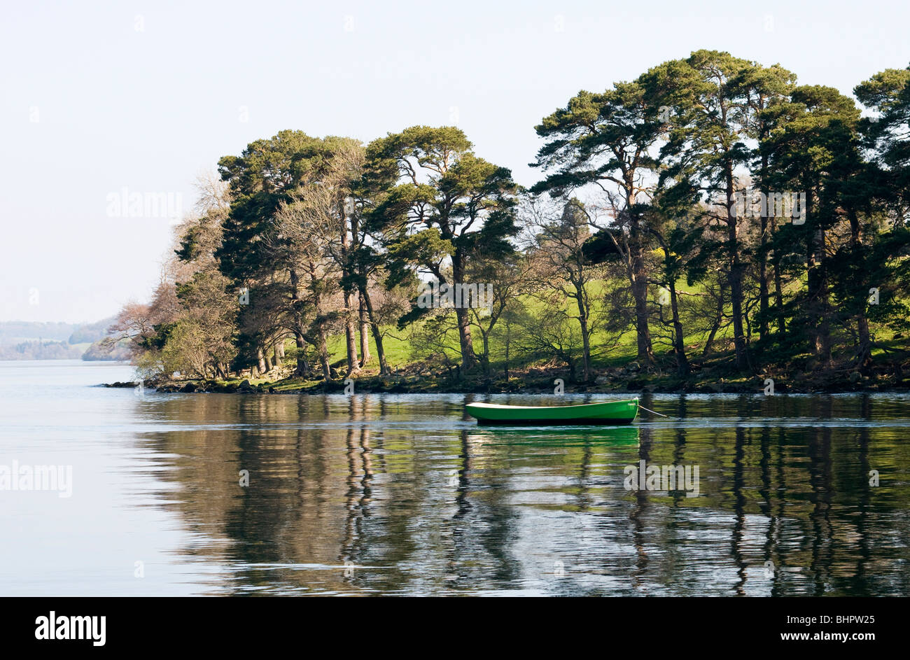 Barca a remi tra l'albero riflessioni sull'Ullswater, Lake District, Cumbria, Regno Unito Foto Stock